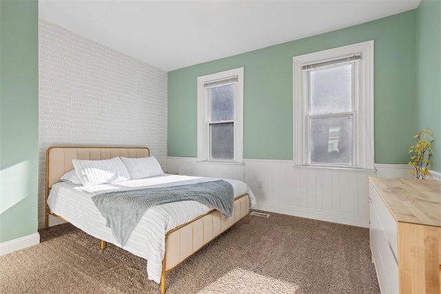 bedroom with carpet, visible vents, and wainscoting