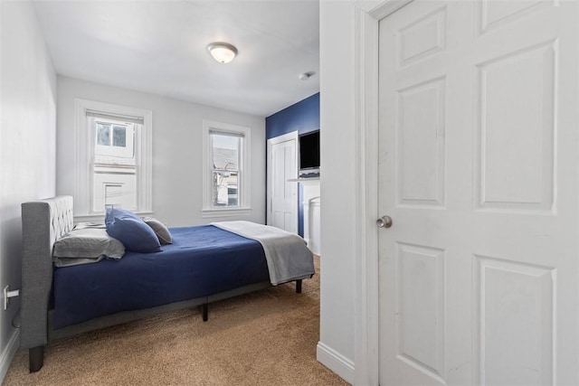 bedroom with baseboards, a closet, and light colored carpet