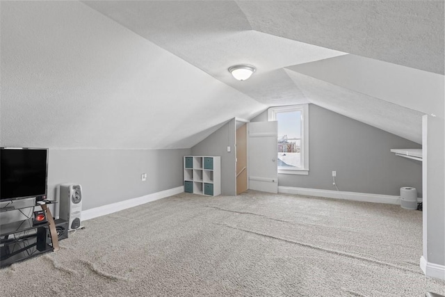 additional living space featuring carpet flooring, vaulted ceiling, a textured ceiling, and baseboards