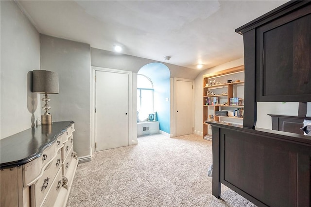 office area featuring arched walkways, light colored carpet, and baseboards