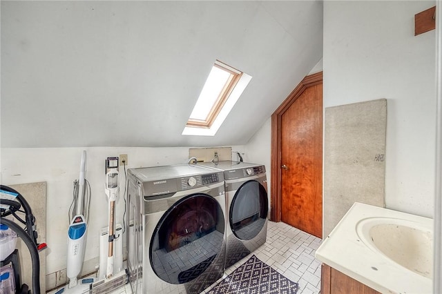 clothes washing area with washer and clothes dryer, a skylight, and a sink