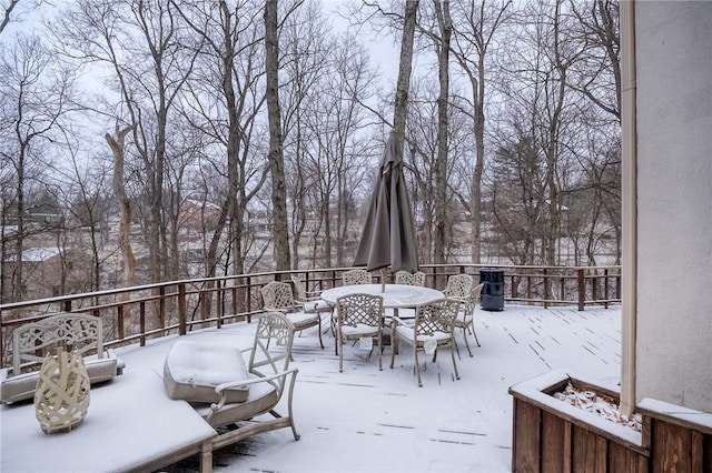 snow covered patio with a deck and outdoor dining space