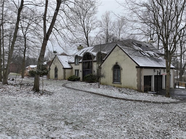 view of front of property with a shingled roof, a chimney, and stucco siding