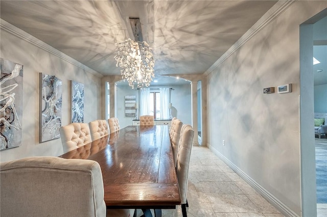 dining space with decorative columns, an inviting chandelier, ornamental molding, stone finish flooring, and baseboards