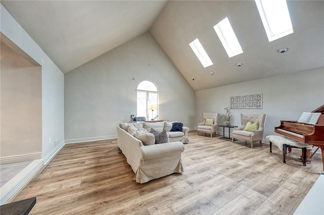 sitting room with a skylight, light wood-style flooring, high vaulted ceiling, and baseboards