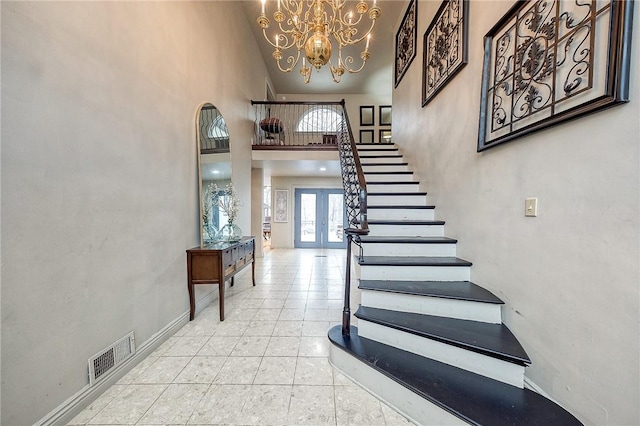 foyer featuring french doors, visible vents, stairway, a towering ceiling, and baseboards