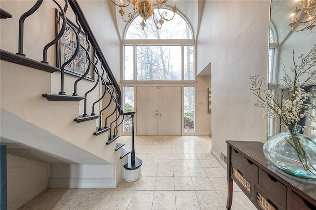 entryway with light tile patterned floors, a notable chandelier, a high ceiling, baseboards, and stairway