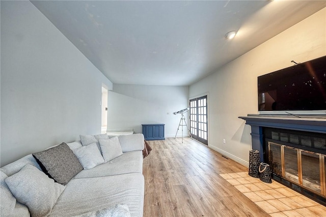 living room featuring a fireplace with flush hearth, wood finished floors, and baseboards