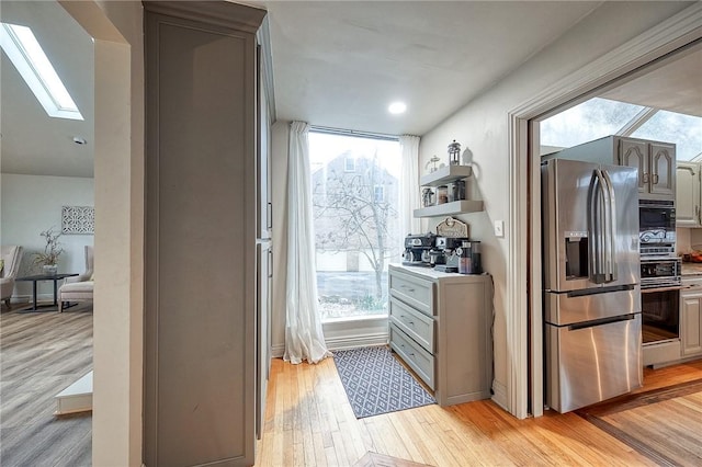 kitchen featuring plenty of natural light, a skylight, range, and stainless steel fridge with ice dispenser