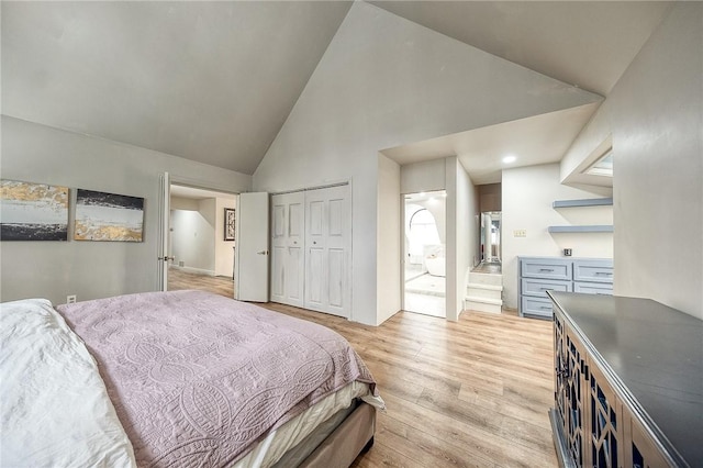 bedroom featuring high vaulted ceiling, a closet, and light wood-style flooring