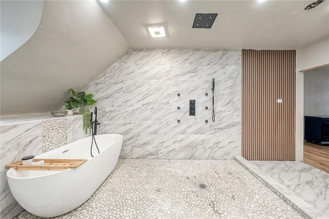 full bath featuring tile walls, vaulted ceiling, a freestanding bath, and tiled shower