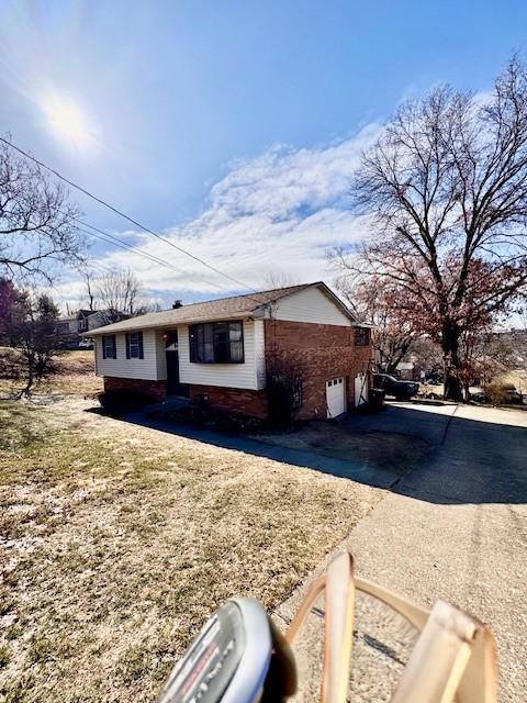 view of front of home featuring driveway, a garage, and brick siding