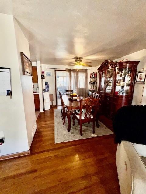 dining area with a ceiling fan, dark wood-style flooring, and baseboards