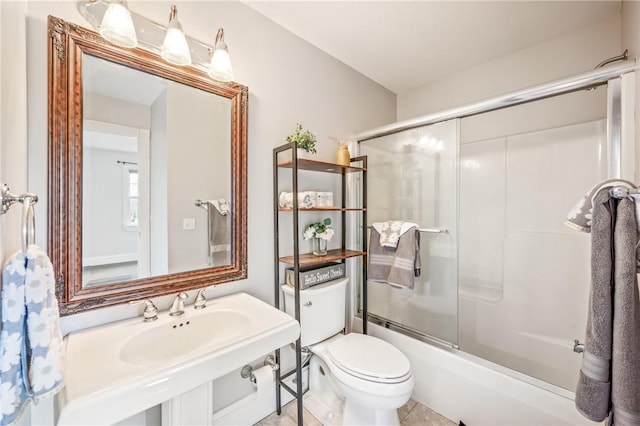 bathroom featuring bath / shower combo with glass door, a sink, and toilet