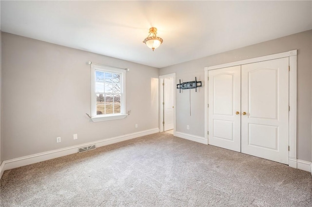 unfurnished bedroom featuring baseboards, a closet, visible vents, and carpet flooring