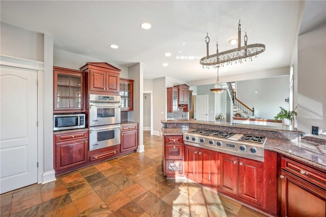 kitchen featuring appliances with stainless steel finishes, recessed lighting, pendant lighting, and glass insert cabinets