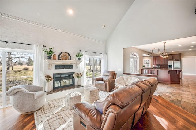 living room with high vaulted ceiling, a glass covered fireplace, light wood finished floors, and recessed lighting