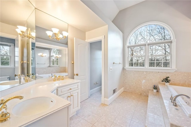 full bath with tile patterned flooring, toilet, a sink, a bath, and an inviting chandelier