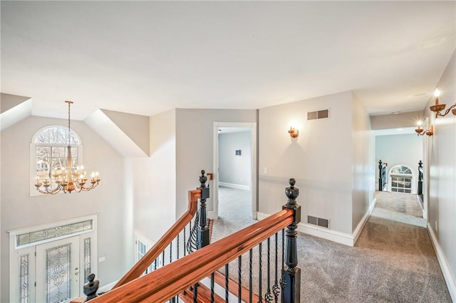 hall with carpet floors, visible vents, a notable chandelier, and an upstairs landing