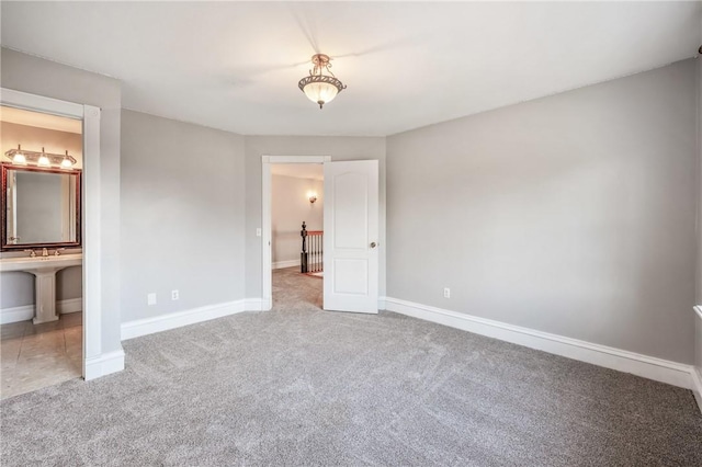 unfurnished bedroom with ensuite bathroom, carpet, and baseboards