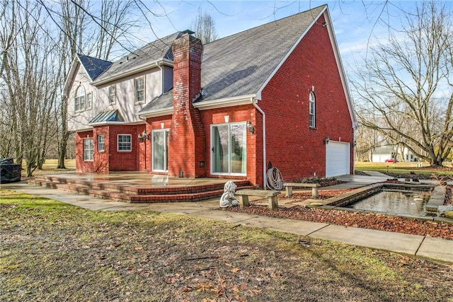 back of property with a garage, a chimney, and brick siding