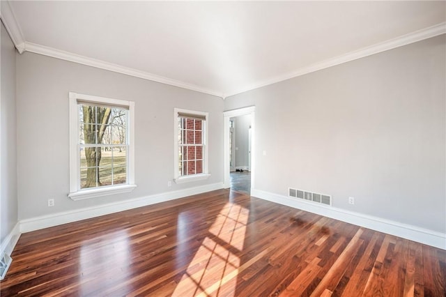 empty room with crown molding, wood finished floors, visible vents, and baseboards