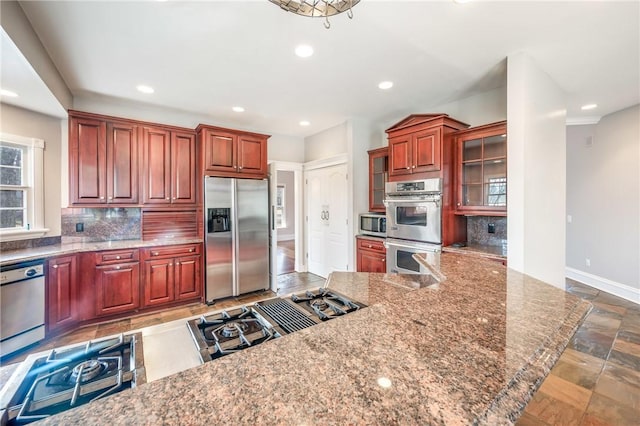 kitchen featuring recessed lighting, stainless steel appliances, baseboards, decorative backsplash, and glass insert cabinets