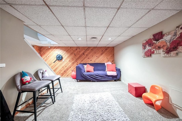 interior space featuring carpet, a paneled ceiling, recessed lighting, visible vents, and wood walls