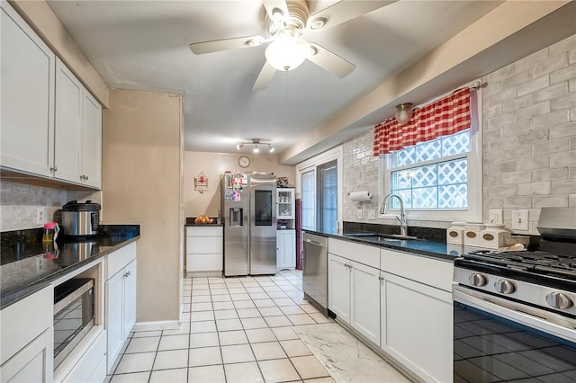 kitchen with light tile patterned floors, stainless steel appliances, tasteful backsplash, white cabinets, and a sink