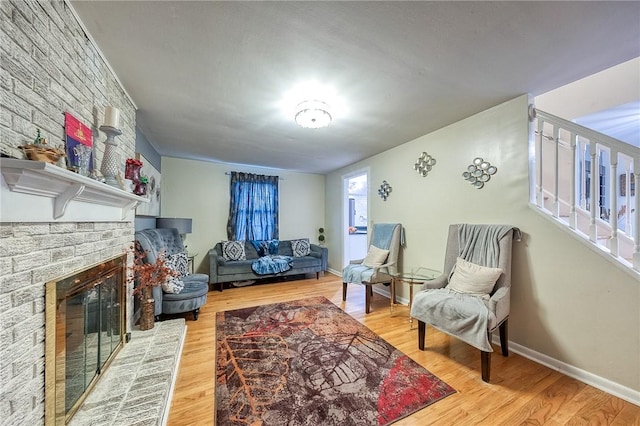 living room featuring a fireplace, baseboards, and wood finished floors