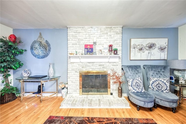 living area featuring a brick fireplace and wood finished floors