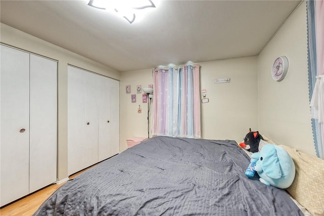 bedroom with multiple closets and wood finished floors