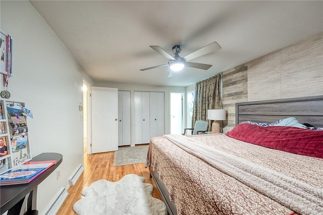 bedroom featuring ceiling fan, an accent wall, a baseboard radiator, and light wood-style flooring