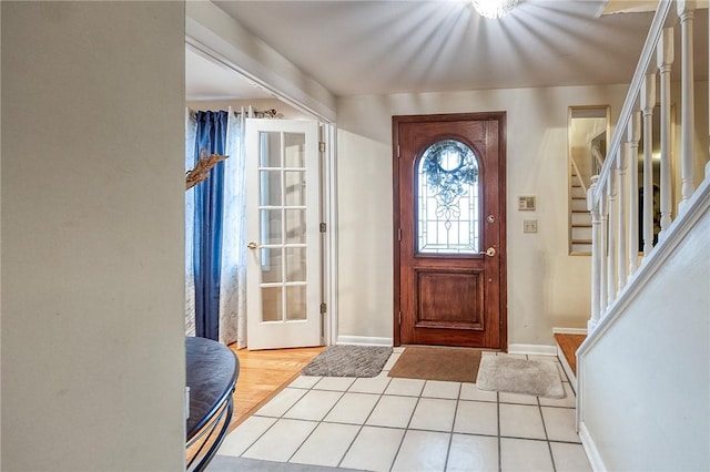 foyer with stairs, light tile patterned floors, and baseboards