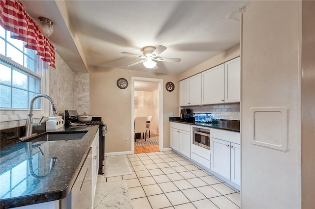 kitchen featuring white cabinets, ceiling fan, appliances with stainless steel finishes, backsplash, and a sink