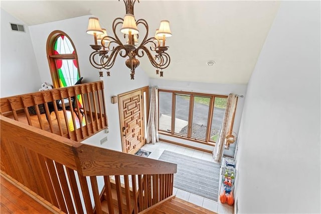 interior space featuring a chandelier, lofted ceiling, visible vents, and wood finished floors