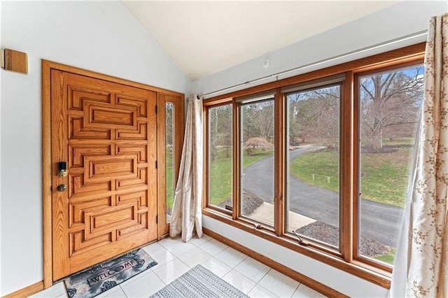 entryway with vaulted ceiling, baseboards, and light tile patterned floors