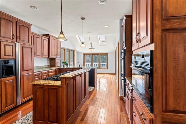 kitchen featuring a peninsula, light stone countertops, hardwood / wood-style floors, decorative light fixtures, and stainless steel gas stovetop