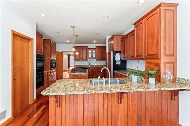 kitchen with dark wood-type flooring, a peninsula, black appliances, a sink, and recessed lighting