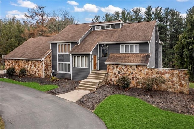 view of front facade with stone siding and roof with shingles