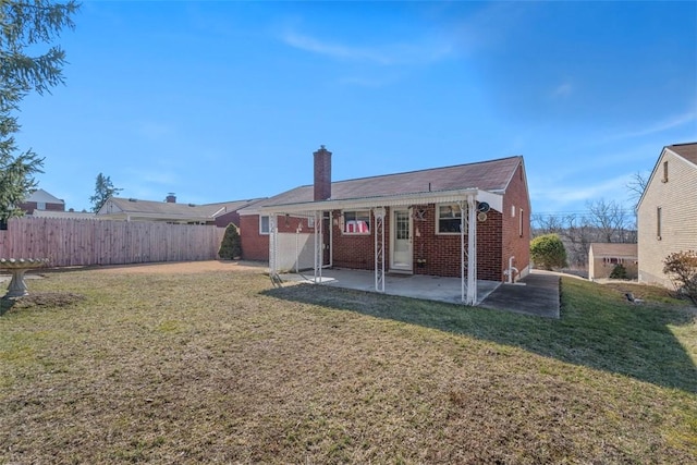 back of property with a chimney, fence, a yard, a patio area, and brick siding