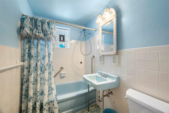 full bathroom with toilet, wainscoting, tile walls, and shower / tub combo with curtain