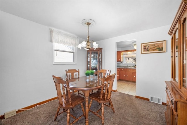 dining room featuring baseboards, light colored carpet, visible vents, and a notable chandelier