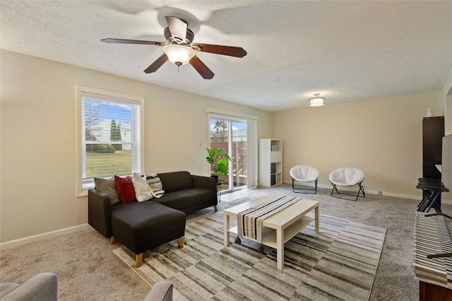 living room featuring carpet floors, a textured ceiling, baseboards, and a ceiling fan