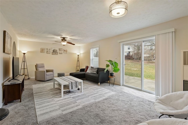 carpeted living room featuring a textured ceiling, a ceiling fan, and baseboards