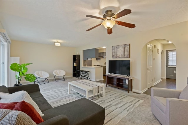 living area featuring arched walkways, carpet flooring, and baseboards