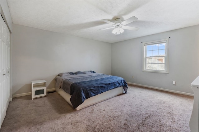 carpeted bedroom featuring a ceiling fan, a closet, a textured ceiling, and baseboards