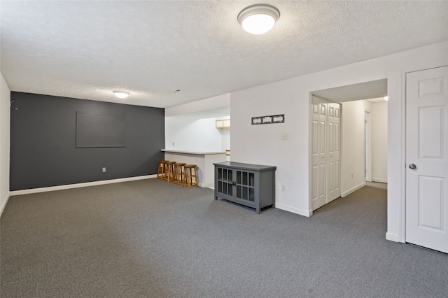 interior space with carpet floors, a textured ceiling, and baseboards