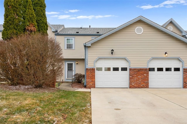 multi unit property featuring concrete driveway, brick siding, and an attached garage