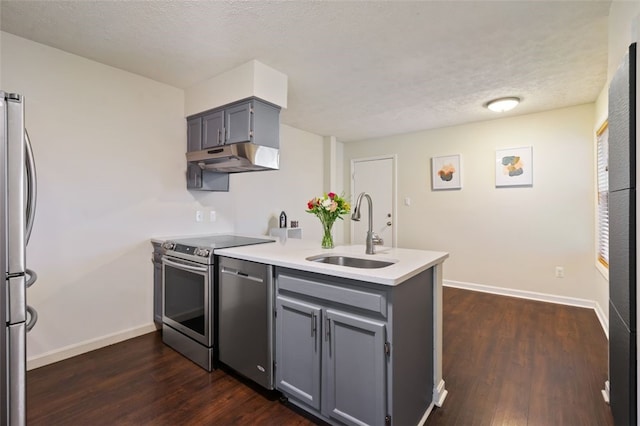 kitchen with appliances with stainless steel finishes, a peninsula, gray cabinetry, under cabinet range hood, and a sink